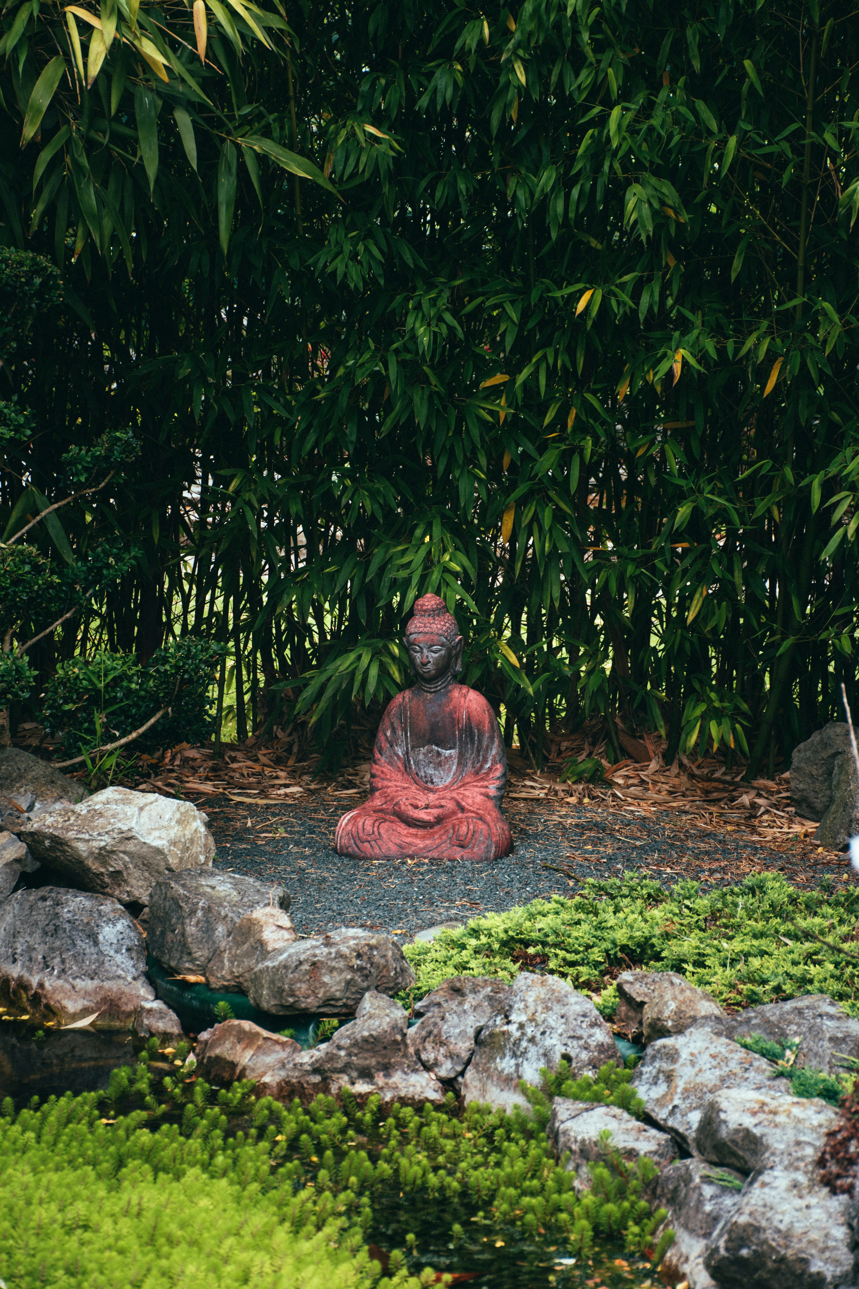 une statue d’une personne assise dans un jardin