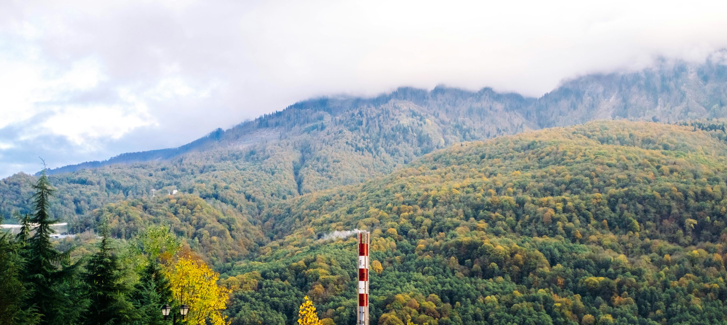 torre vermelha e branca no campo de grama verde perto de montanhas verdes durante o dia