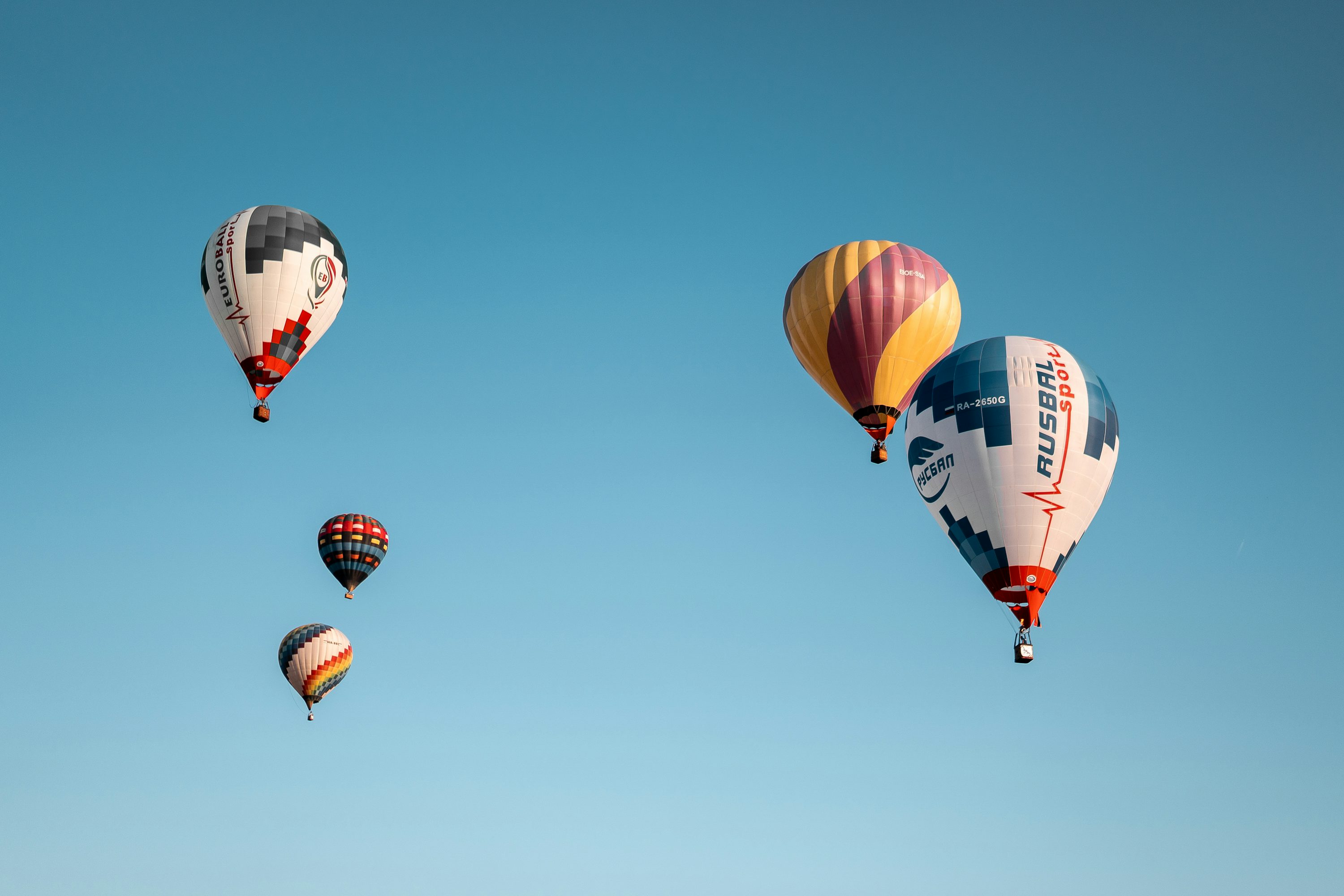 Un gruppo di mongolfiere che volano attraverso un cielo blu