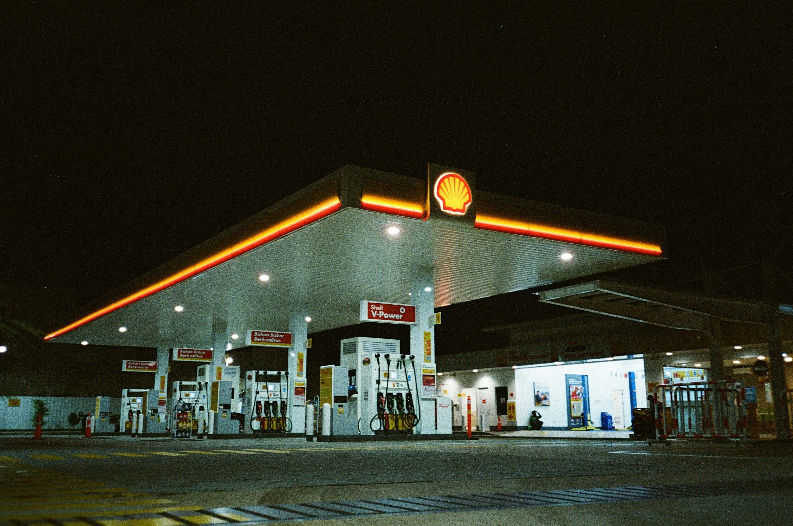 Una gasolinera por la noche con una gasolinera iluminada