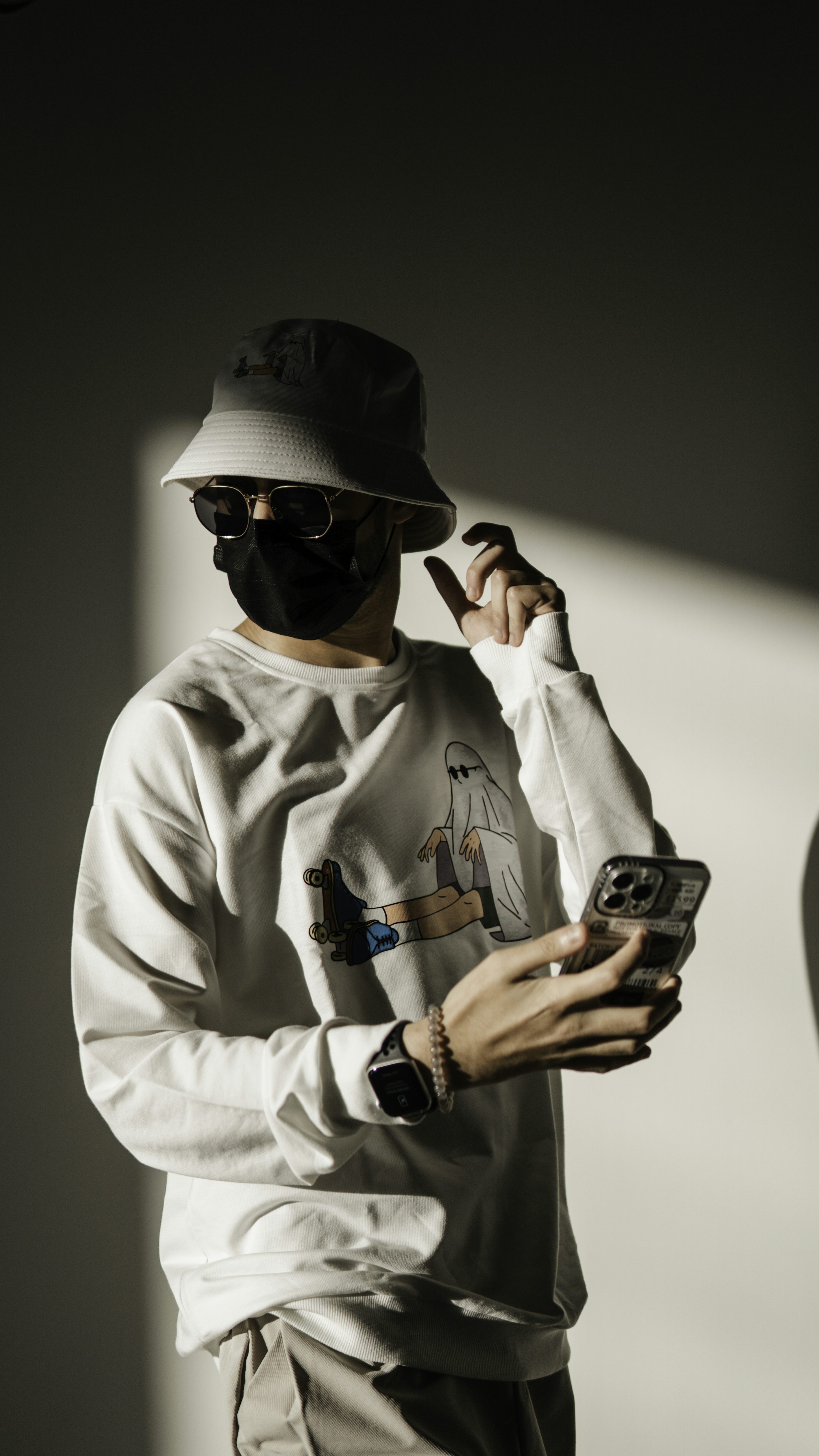 Un hombre con una sudadera blanca y un sombrero sosteniendo un teléfono celular