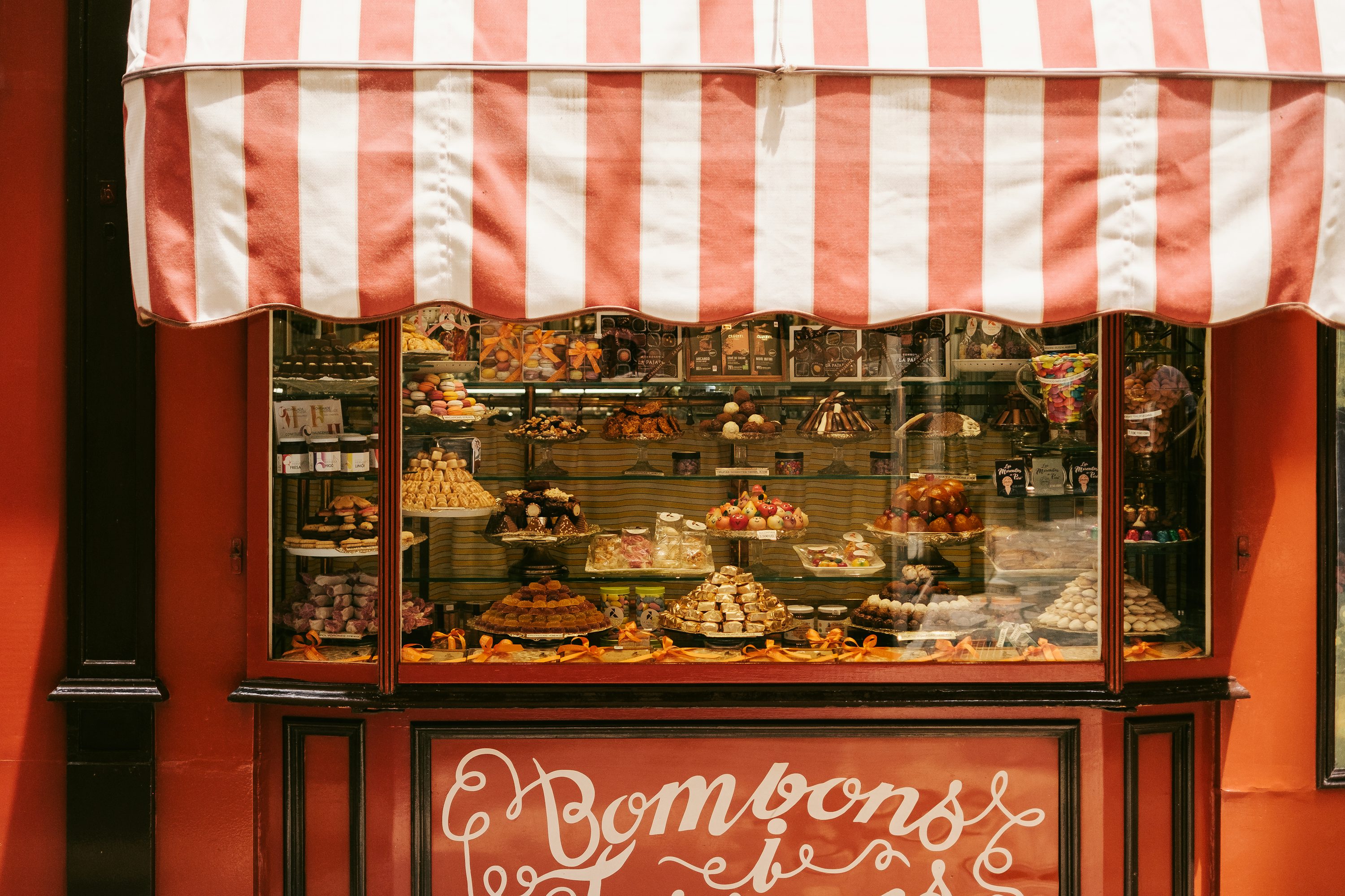 Un frente de tienda con toldo rojo y blanco