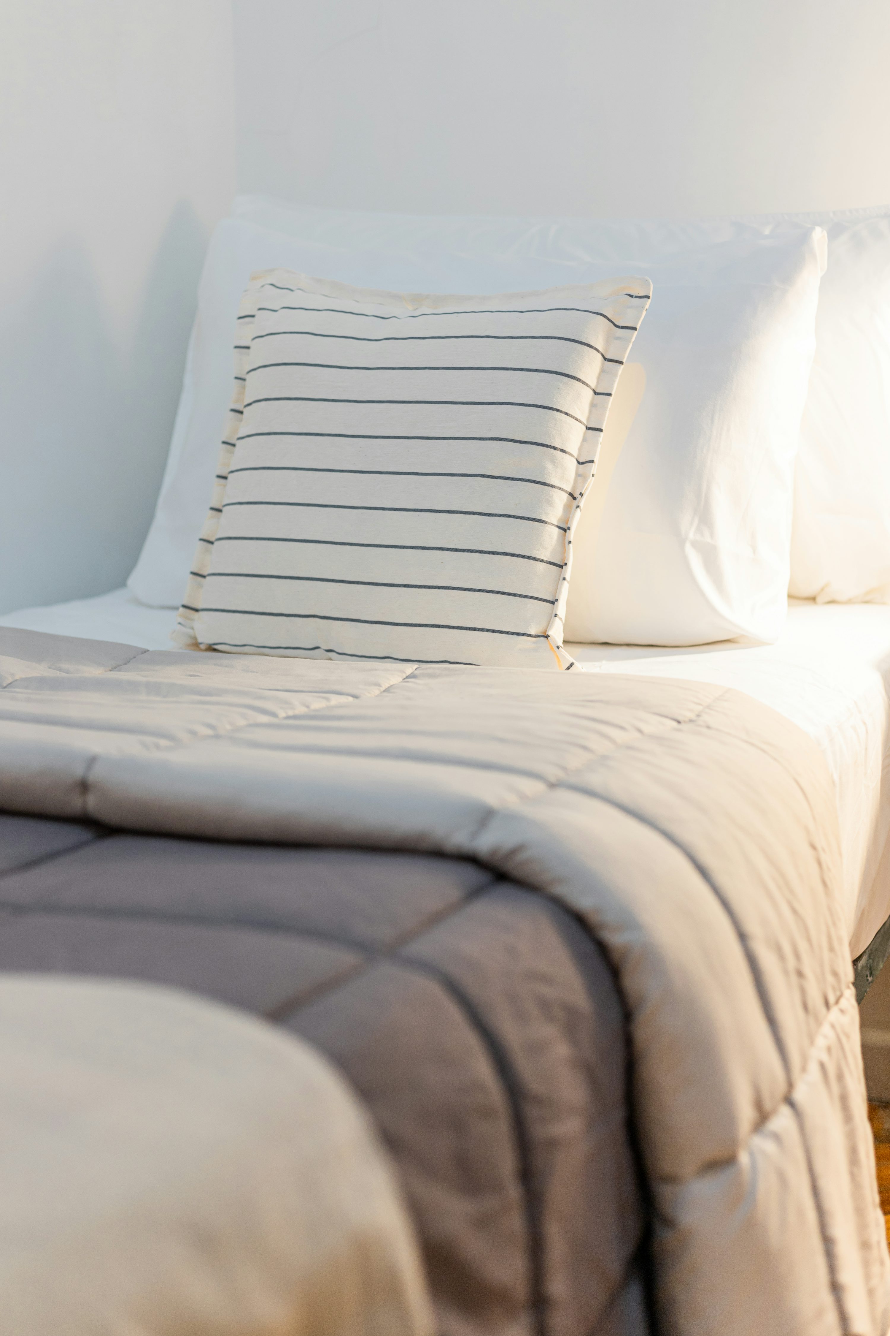 una cama con edredón blanco y dos almohadas