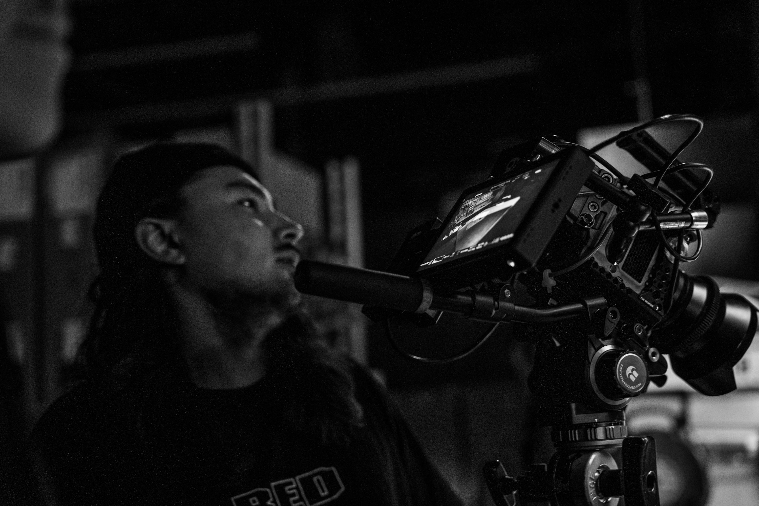 a man standing next to a camera on a tripod