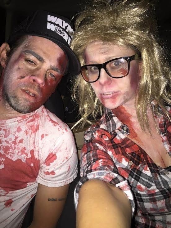 Two people covered in blood dressed as zombies