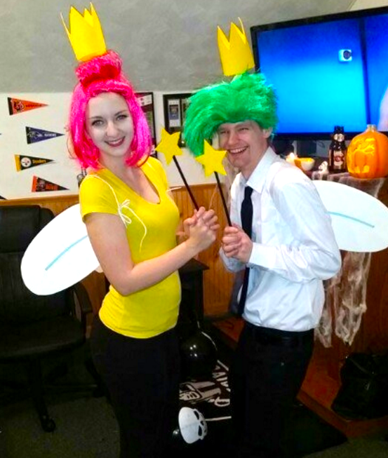 One girl in a pink wig with wings and one boy in a green wig with wings