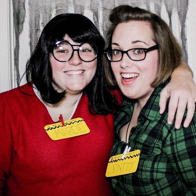 Two girls wearing glasses and name tags as characters from the Peanuts