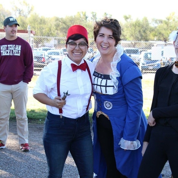 One person wearing suspenders and a bowtie and the other person wearing a blue dress with ruffles