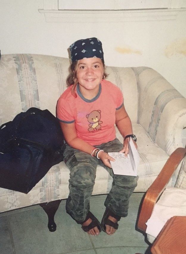A young person in sandals, camo pants, and a do-rag sitting on a couch