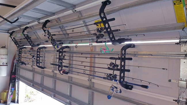 inside of garage door half open with racks on the inside of the garage doors with the fishing poles organized horizontal