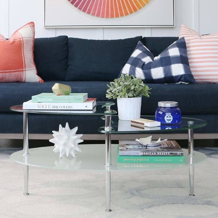 A translucent glass oval table with two clear wave-slash-half-oval-shaped shelves on top