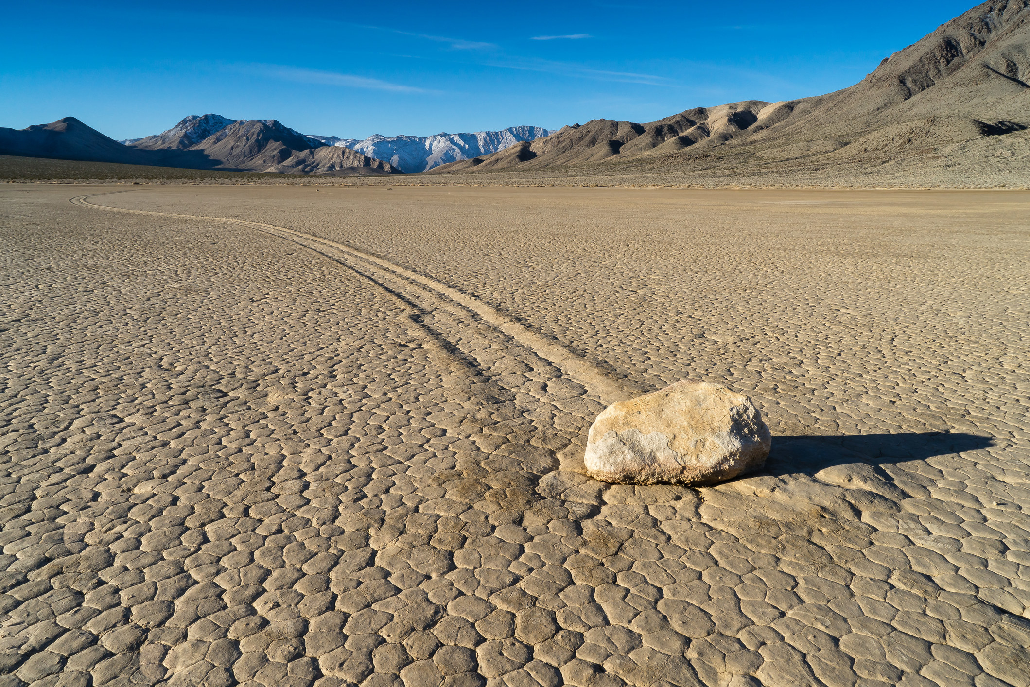 A desert setting with a moving rock&#x27;s imprints in the ground. 