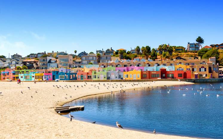 A colorful row of rainbow houses by the beach.