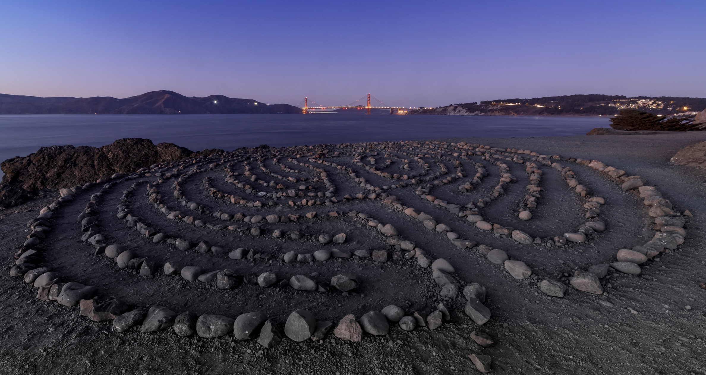 A rock maze overlooking an ocean and city view.