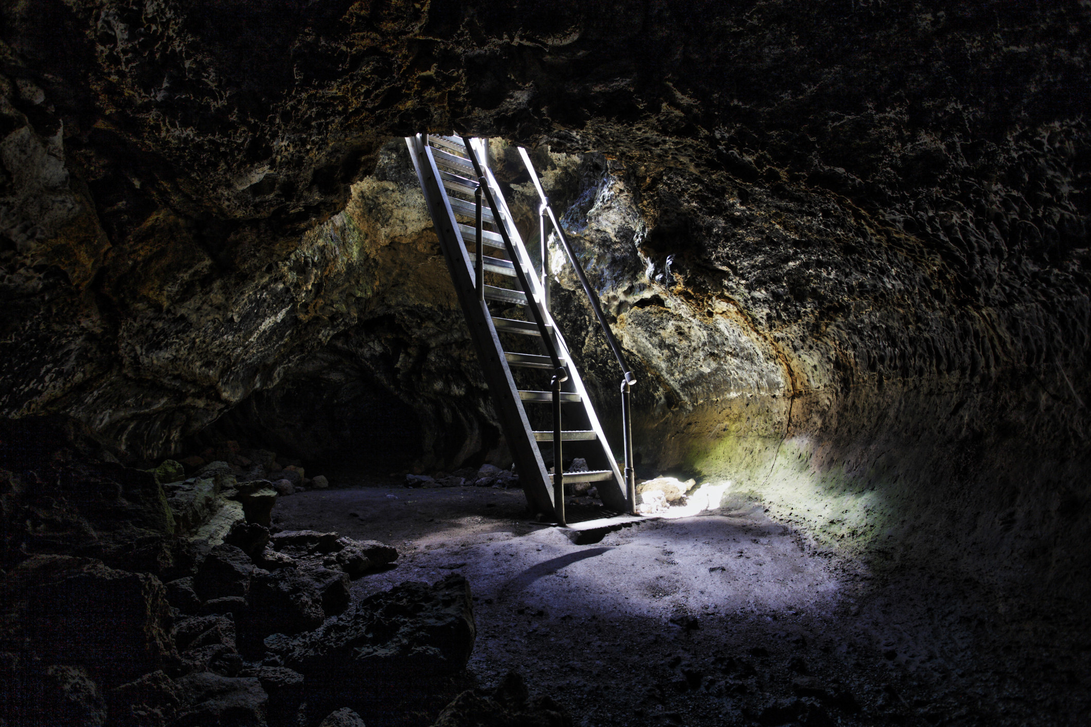 A dark, underground cave with light popping through the top.