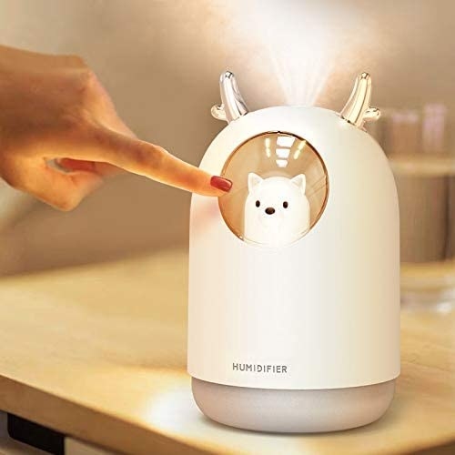 model touching the cool mist humidifier in white with their finger 