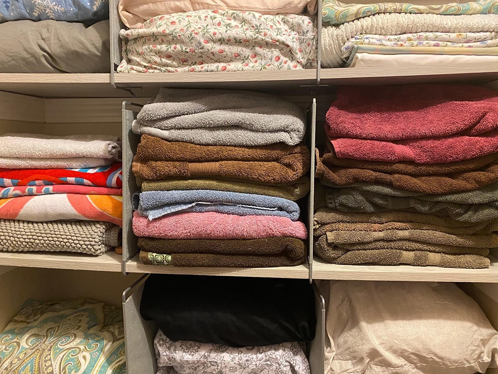 reviewer photo showing shelf dividers used to separate stacks of towels in their linen closet