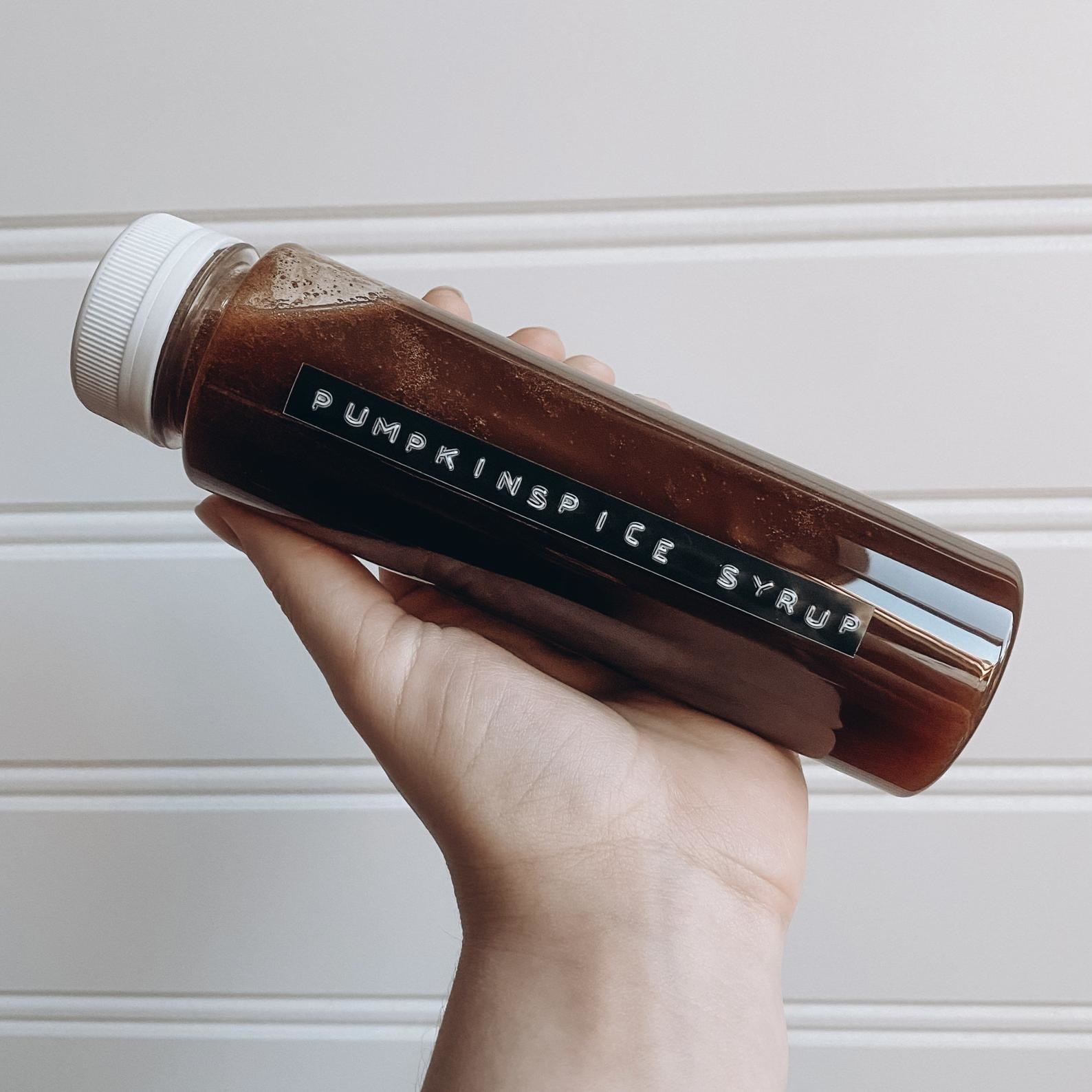 a person holding the bottle of pumpkin simple syrup