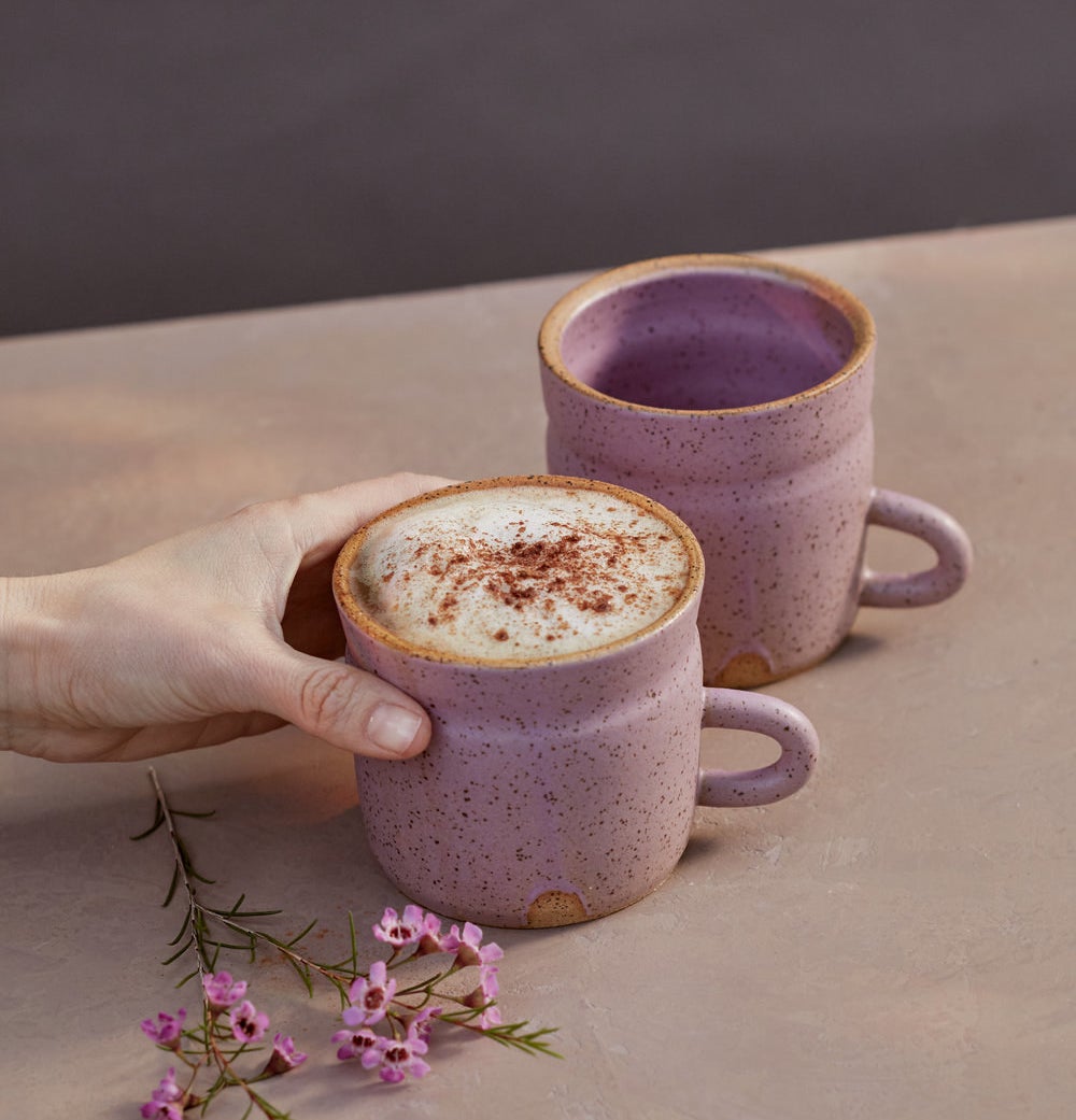 a hand holding the pink speckled stoneware mug