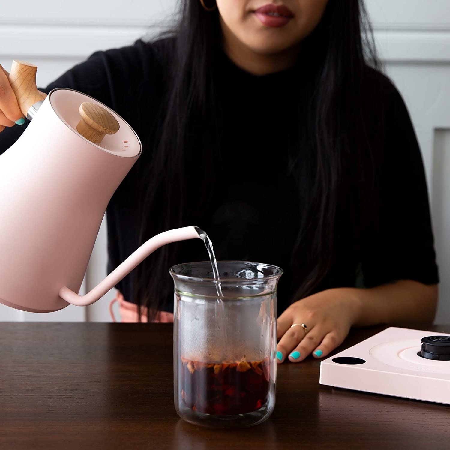 a model pouring water from the pink electric kettle
