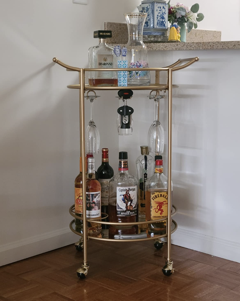 Reviewer&#x27;s bar cart sits in the corner of a dining room and is holding various liquor bottles and barware