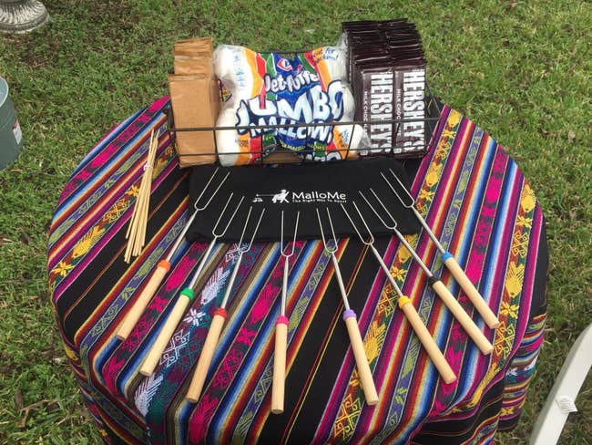 reviewer image of the MalloMe marshmallow roasting sticks splayed out on a table next to a bin of graham crackers, marshmallows, and hershey's chocolate