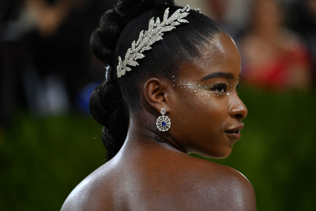 A close up of Amanda Gorman shows off her crystal headband and matching eye make up