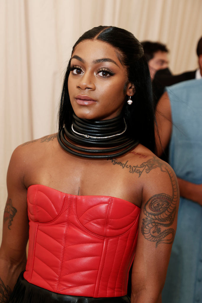 A close up of Sha&#x27;Carri Richardson as she shows off her natural makeup and multiple oversized choker necklaces