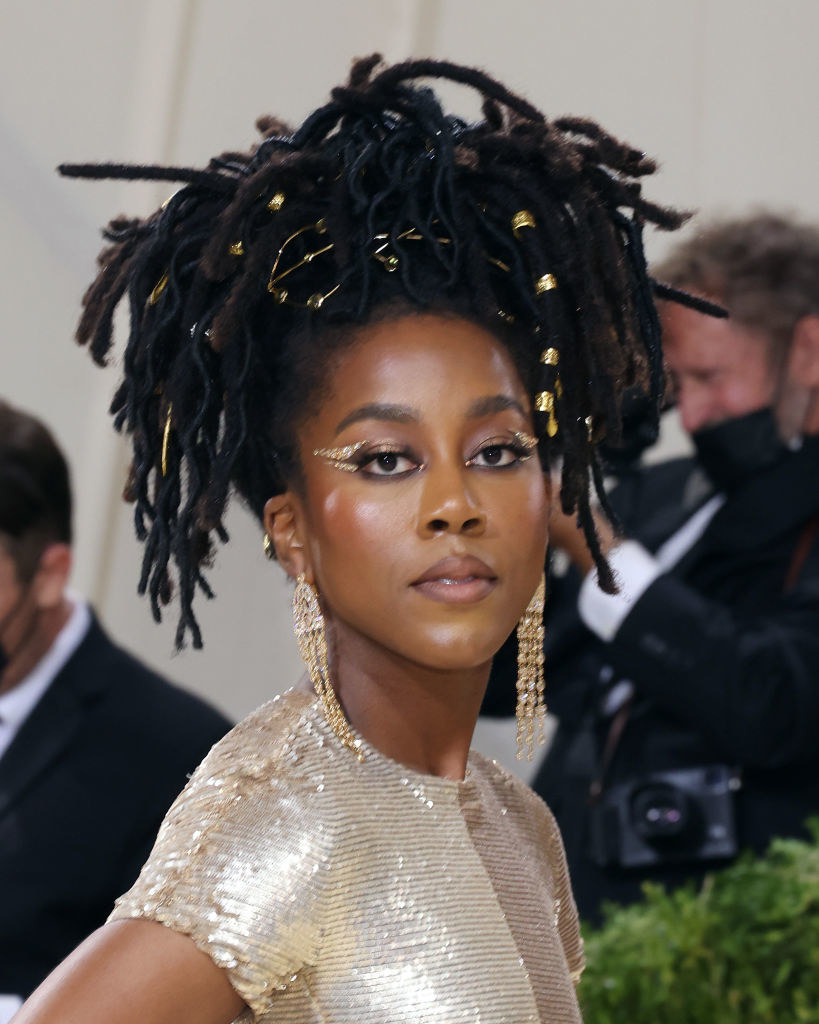 A close up of Tomi Adeyemi as she shows off her glittery eye makeup and dangling earrings