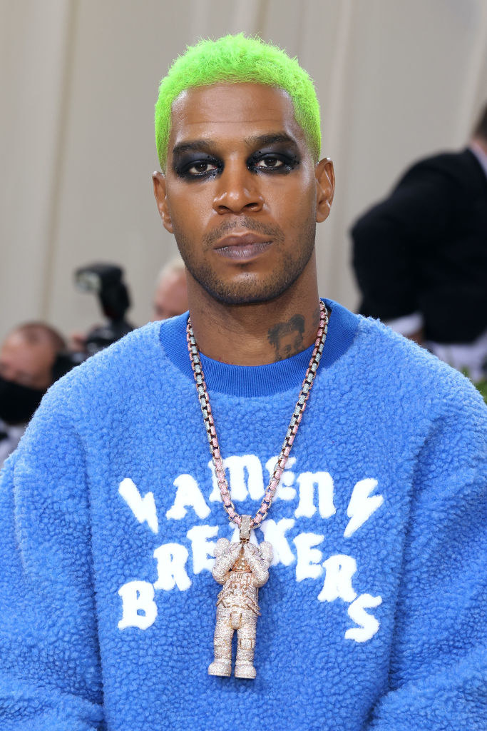 A close up of Kid Cudi as he shows off his dark eye makeup and neon colored hair