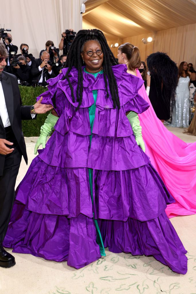 Whoopi Goldberg wears a short sleeve gown with ruffled layers and brightly colored elbow length gloves