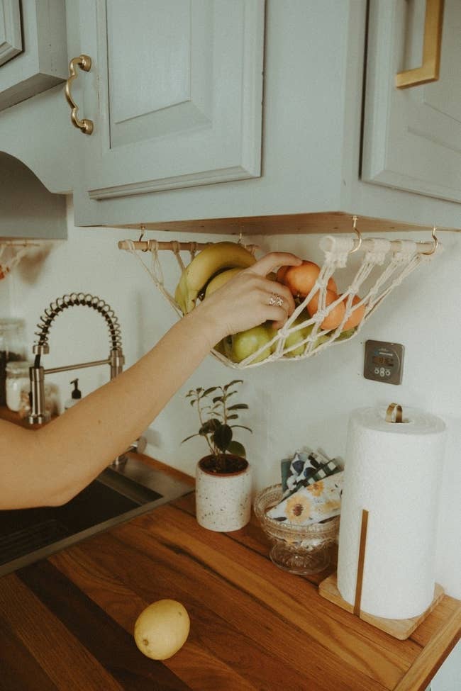 kitchen with a fruit hammock hanging down from the bottom of a cabinet