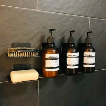 Reviewer's shampoo, conditioner, and body wash bottles are shown on the wall of a shower