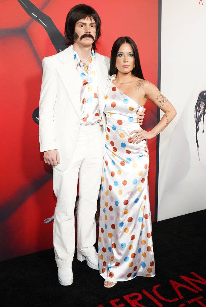 Evan Peters wears a one color suit with a polka dot shirt and Halsey wears a floor length polka dot gown