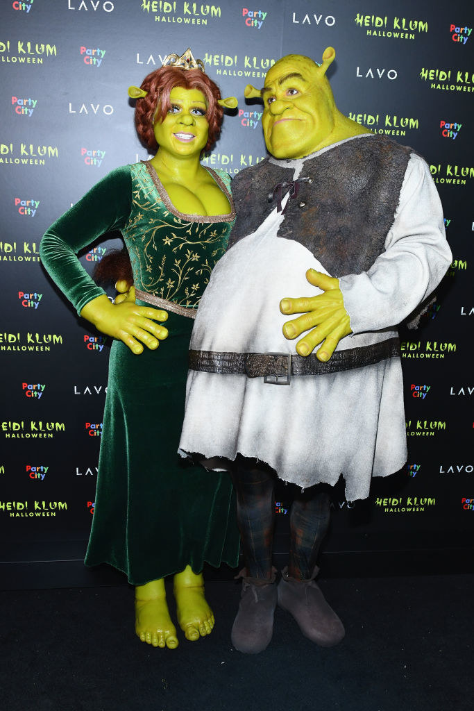 Heidi Klum wears a long sleeve dress with ogre makeup and Tom Kaulitz wears tights and an oversized long sleeve shirt with ogre makeup