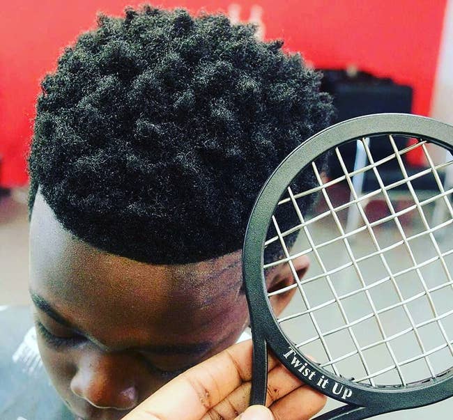 a close up of a model's hair and a hand holding the black twist comb