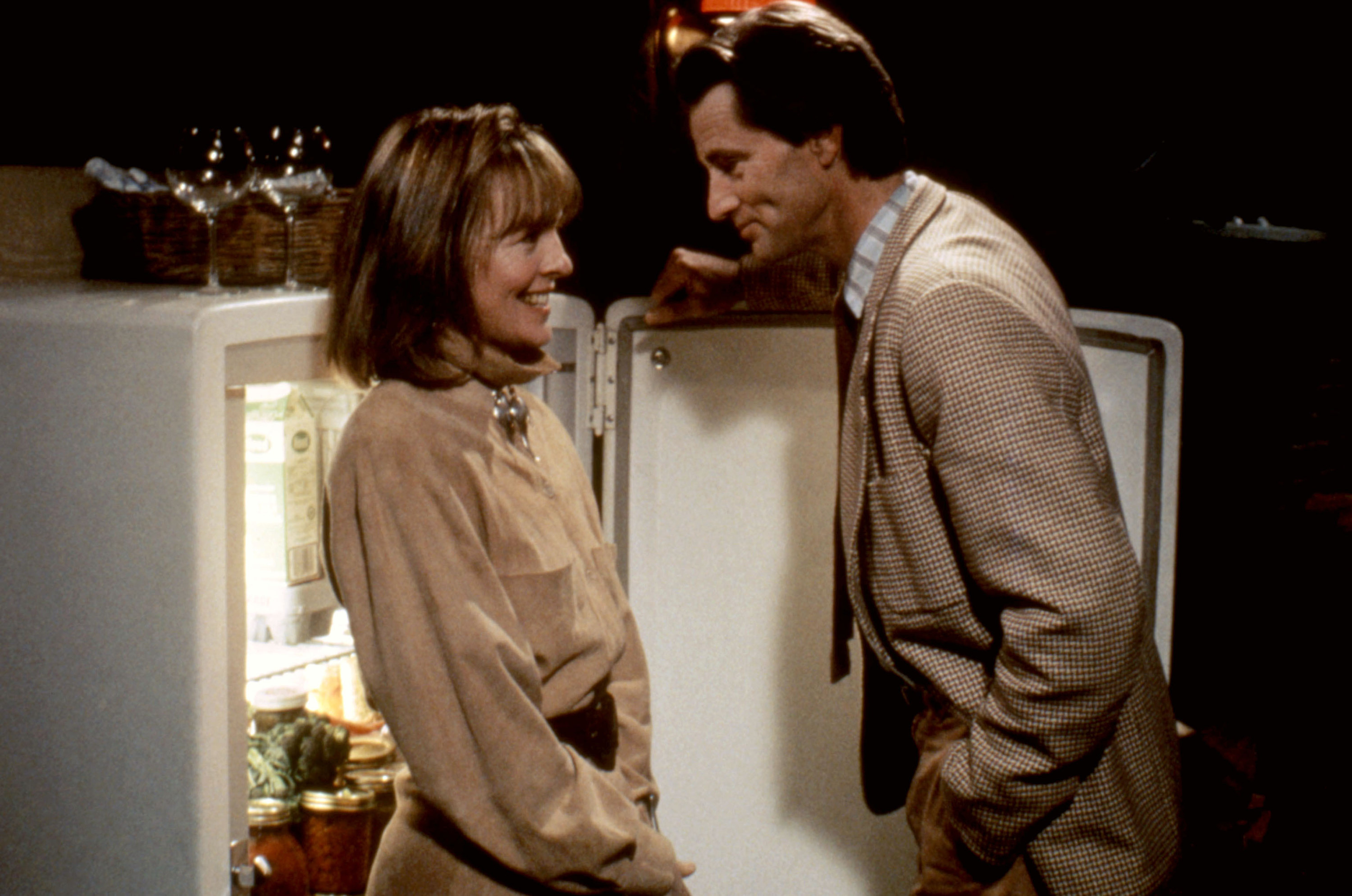 A man and a woman stand in an open refrigerator