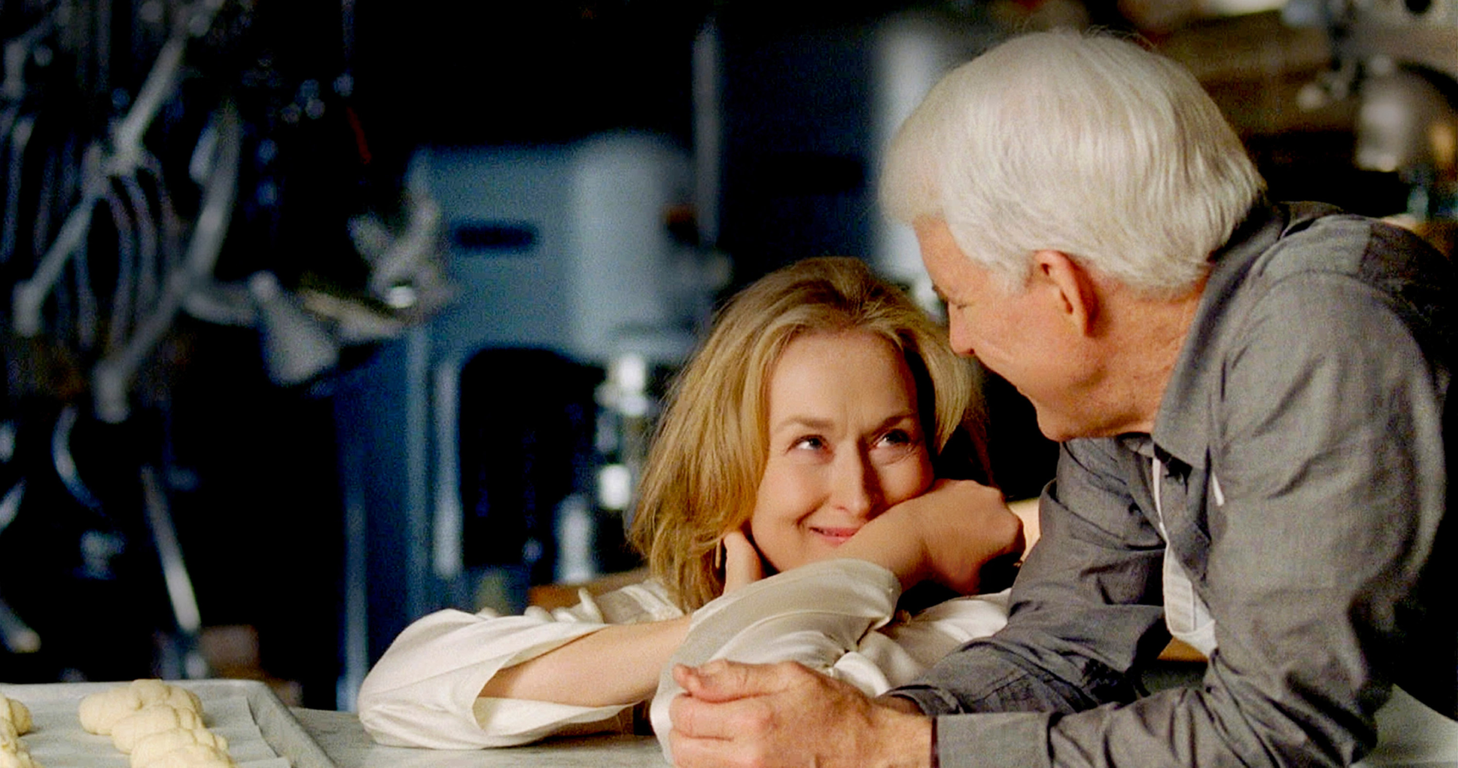 A blonde woman gazes lovingly at a white haired man