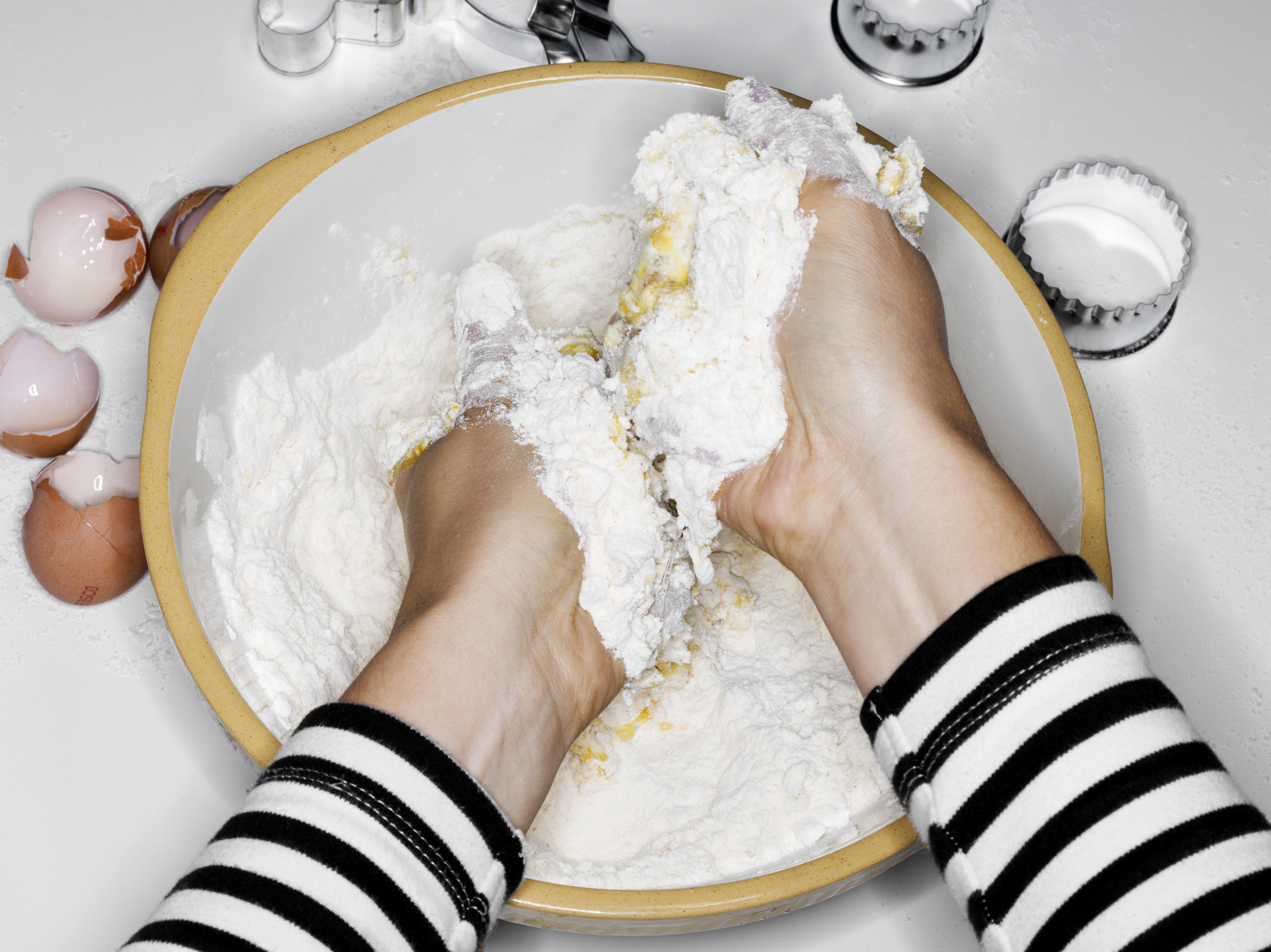 Female hands mixing flour with eggs with hands in a bowl.