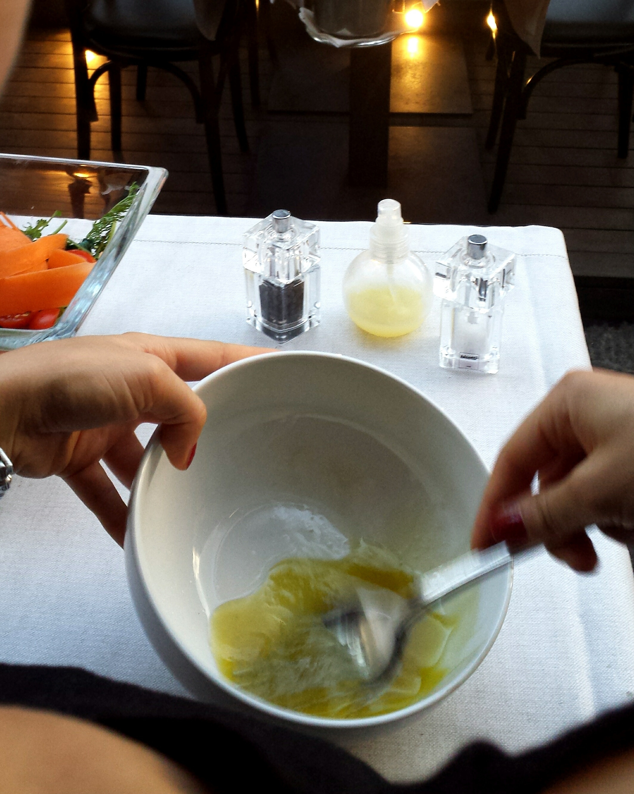 A woman mixing salad dressing in a bowl.