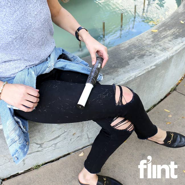 Model using small lint roller to remove hair and fuzz from their pants