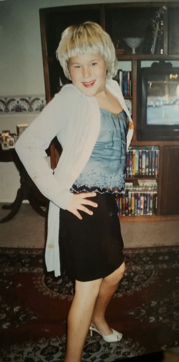 A young person with their hands on their hips, standing in high heels and wearing a skirt and lacy top