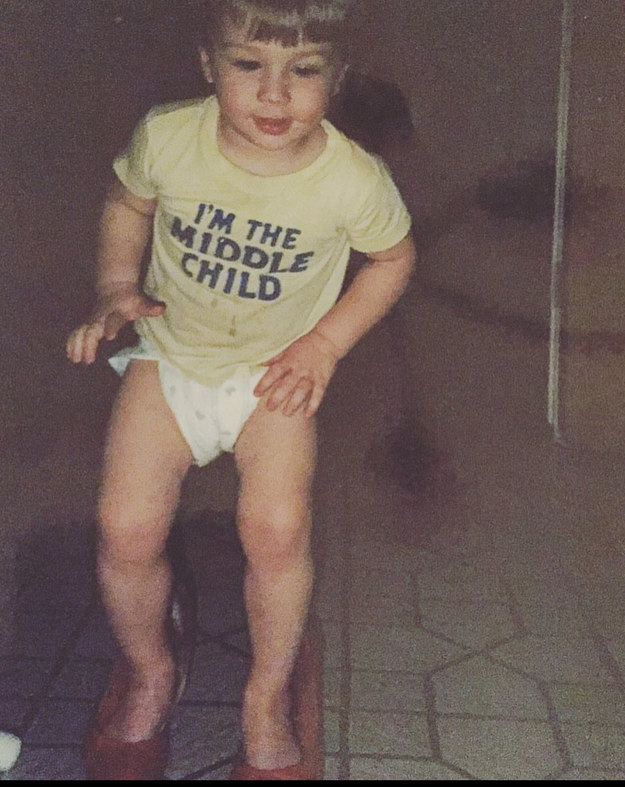 Toddler wearing adult shoes and an &quot;I&#x27;m the middle child&quot; T-shirt