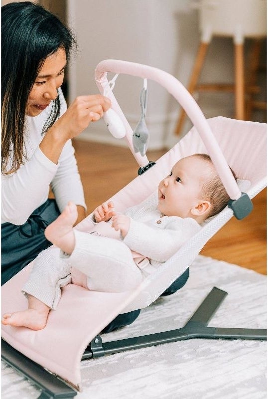 Person plays with a baby in the bouncer