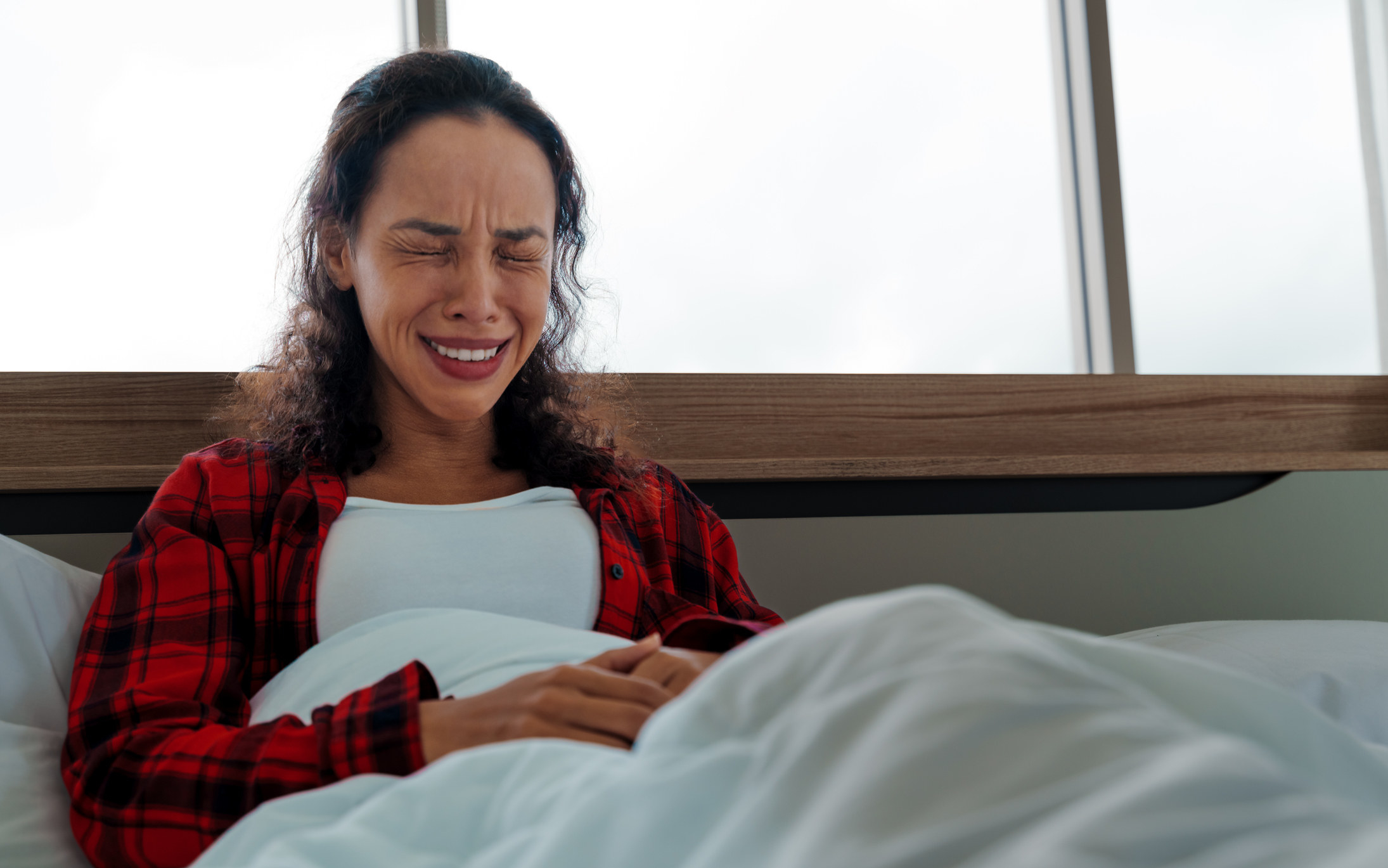 A person in bed grimacing in pain