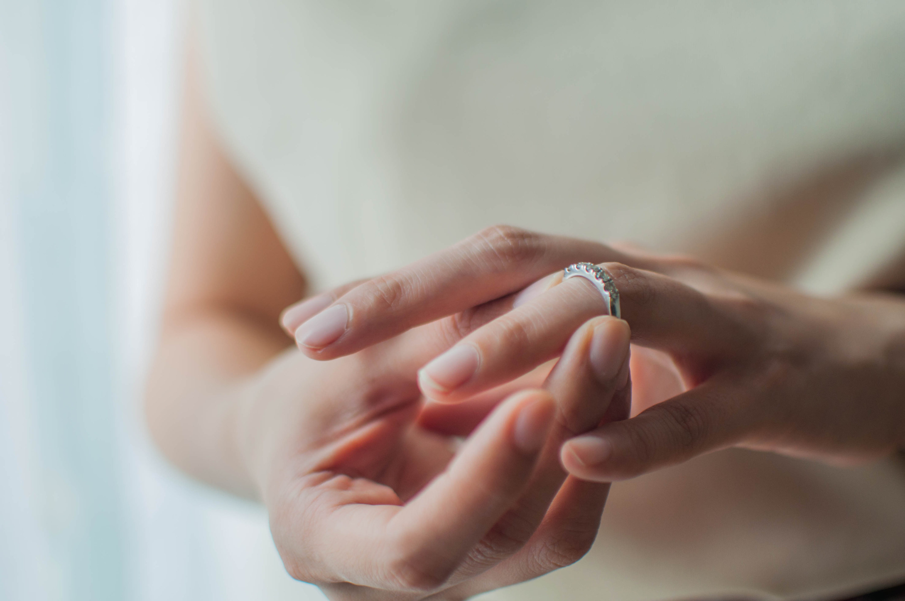 A close-up view of a a person taking off their wedding ring