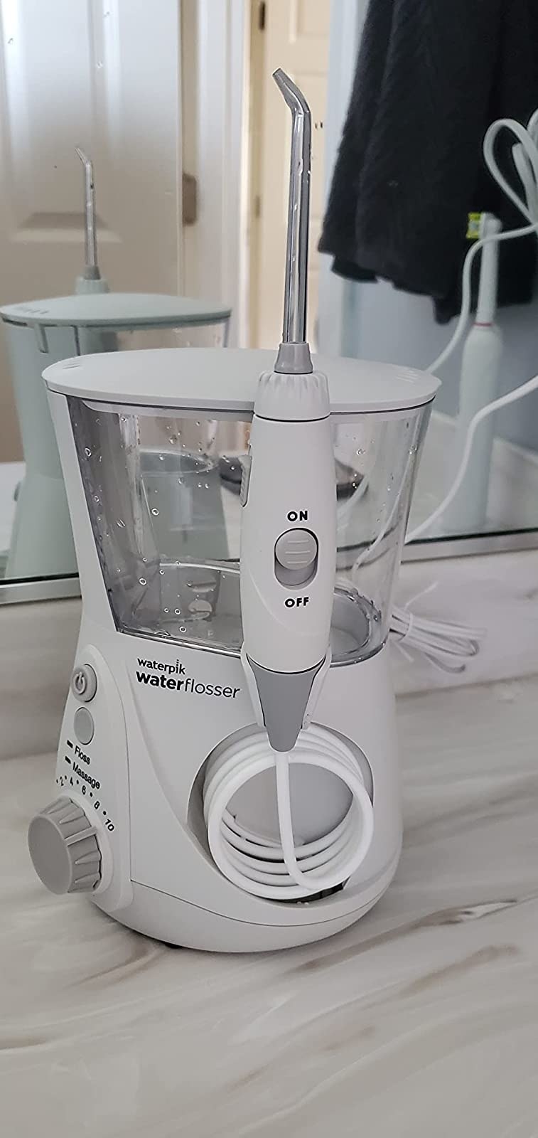 The white waterpik flosser on bathroom counter