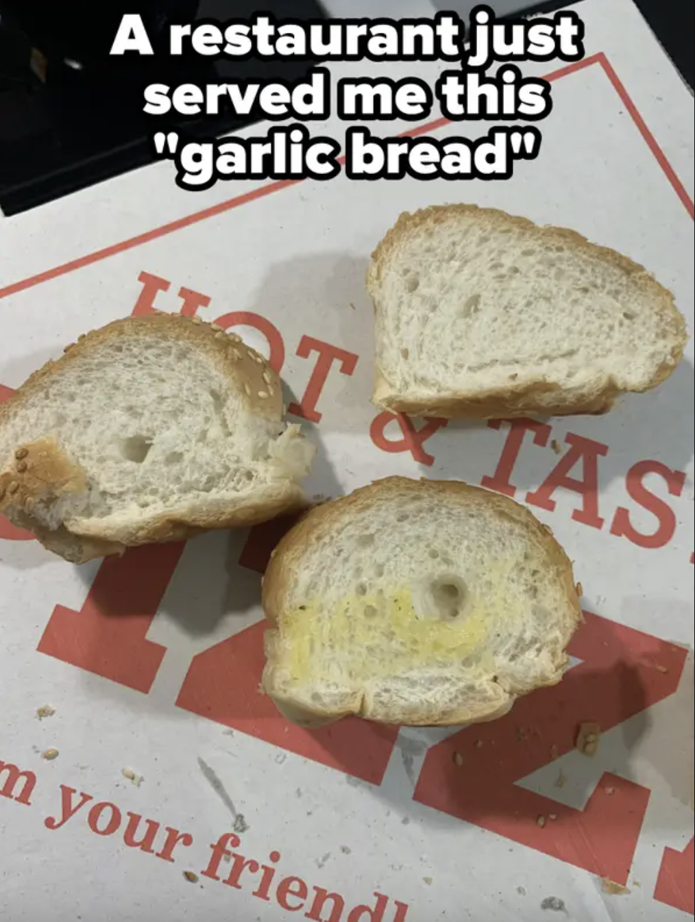 Three pieces of plain bread with faint butter marks labeled as &quot;garlic bread&quot; on a takeaway pizza box with some text