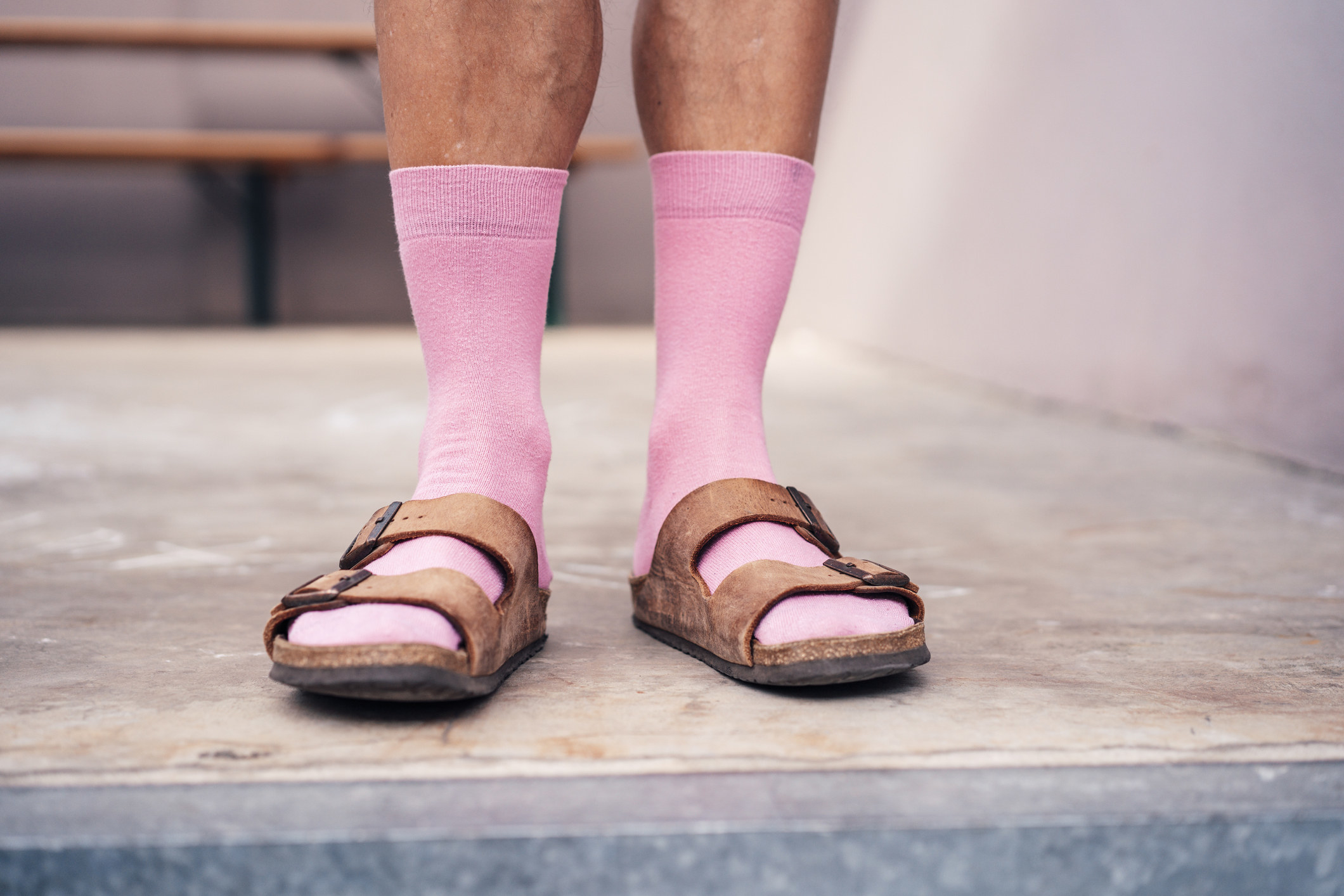 Person wearing a combination of pink socks and brown sandals. The person&#x27;s lower legs are visible
