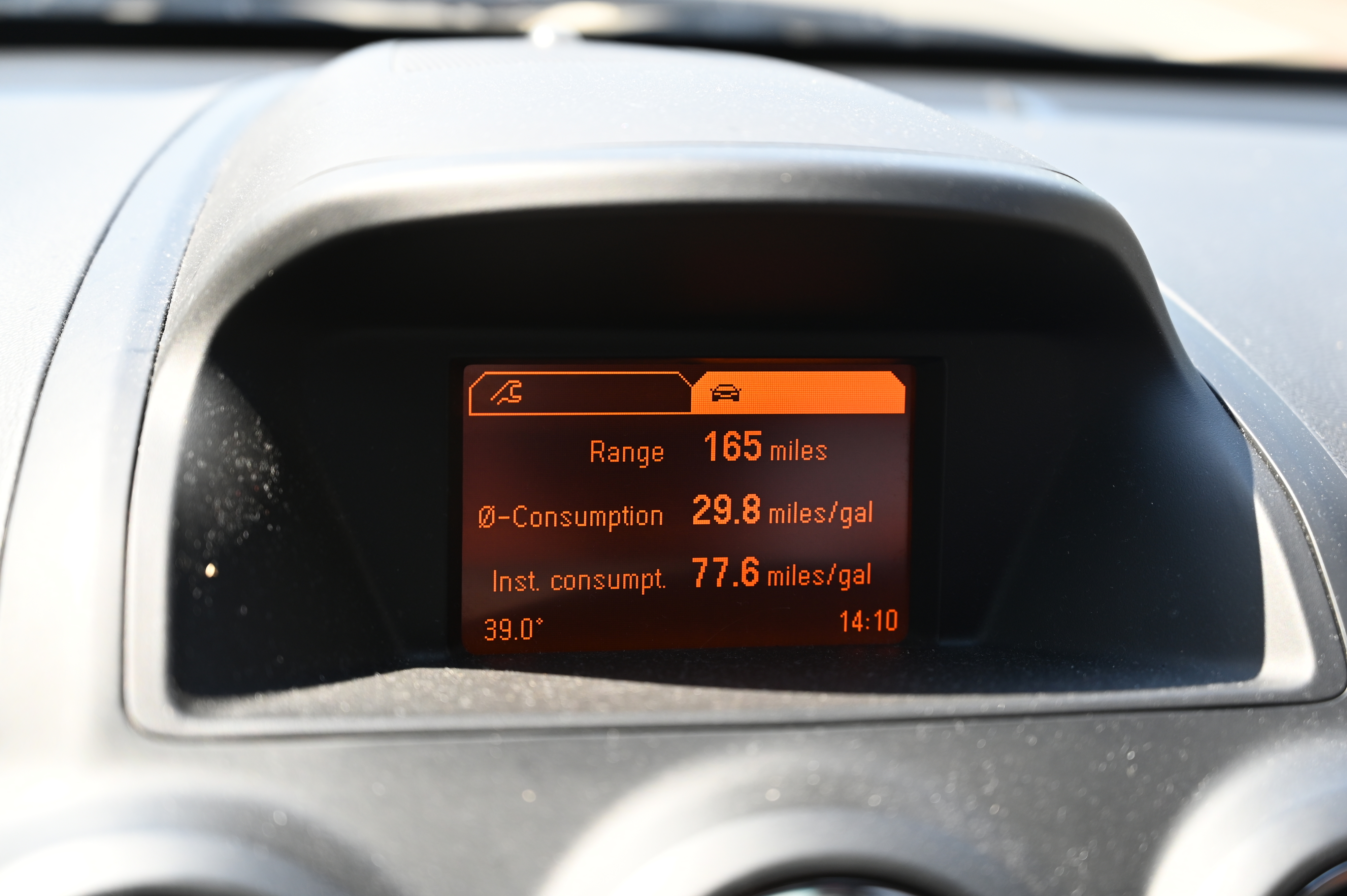 car dashboard showing 77 miles per gallon